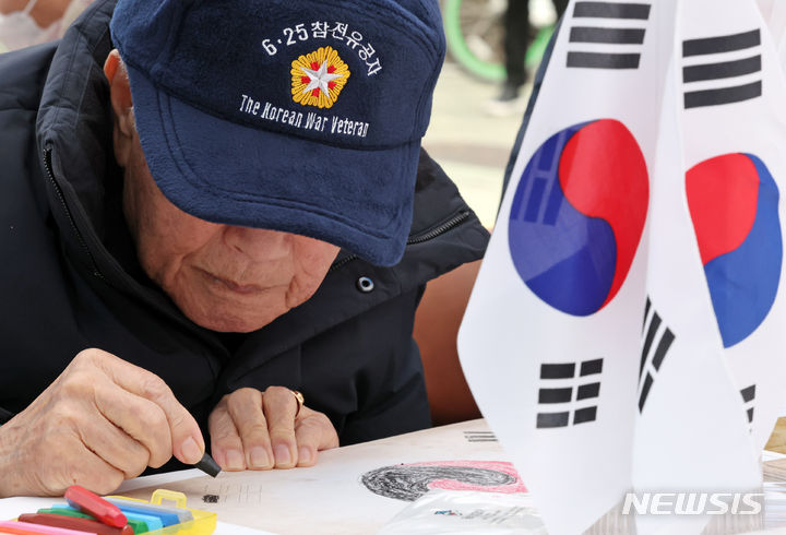 [서울=뉴시스] 조성우 기자 = 29일 오후 서울 은평구 명예도로 '권애라로'에서 열린 진관사 태극기 그리기 행사에서 6·25 참전유공자 어르신이 태극기를 그리고 있다. 2024.02.29. xconfind@newsis.com