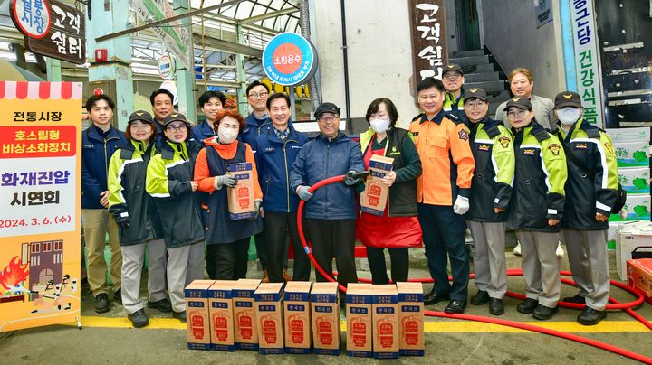 [울산=뉴시스]HD현대사이트솔루션과 울산 동부소방서 관계자들이 6일 울산 동구 월봉시장에서 비상용 소화전 기부 명판식을 갖고 상인들과 함께 기념촬영을 하고 있다. (사진=HD현대사이트솔루션 제공) 2024.03.06. photo@newsis.com *재판매 및 DB 금지