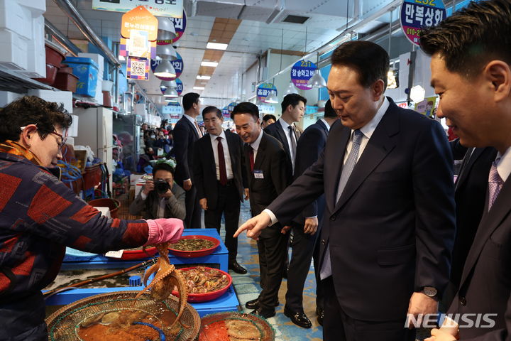 [사천=뉴시스] 조수정 기자 = 윤석열 대통령이 13일 경남 사천시 삼천포용궁수산시장을 찾아 문어를 들어보이는 어패류 상인과 대화하고 있다. (대통령실통신사진기자단) 2024.03.13. chocrystal@newsis.com