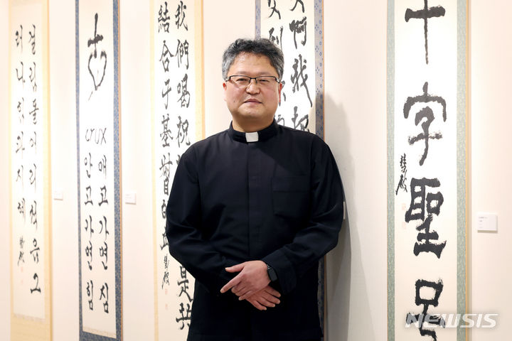 [서울=뉴시스] 박진희 기자 = 정성훈 파비아노 신부가 지난 13일 서울 명동대성당 지하 전시장인 '갤러리 1898'에서 뉴시스 인터뷰 앞서 사진 촬영을 하고 있다. 서예가 정 신부를 비롯한 한만옥 토마스 신부, 남덕희 베드로 신부, 용하진 실바노 신부, 도현우 안토니오 신부 5명의 사제들은 '십자가 영성'을 주제로 지난 13일부터 합동 서예 전시회를 하고 있다. 2024.03.16. pak7130@newsis.com