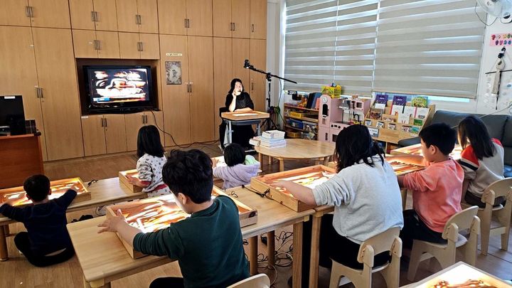 [밀양=뉴시스] 겨울방학 프로그램인 샌드아트 활동에서 아이들이 LED 모래판 위에 그림을 그리고 있다. (사진=밀양시 제공) 2024.03.17. photo@newsis.com *재판매 및 DB 금지