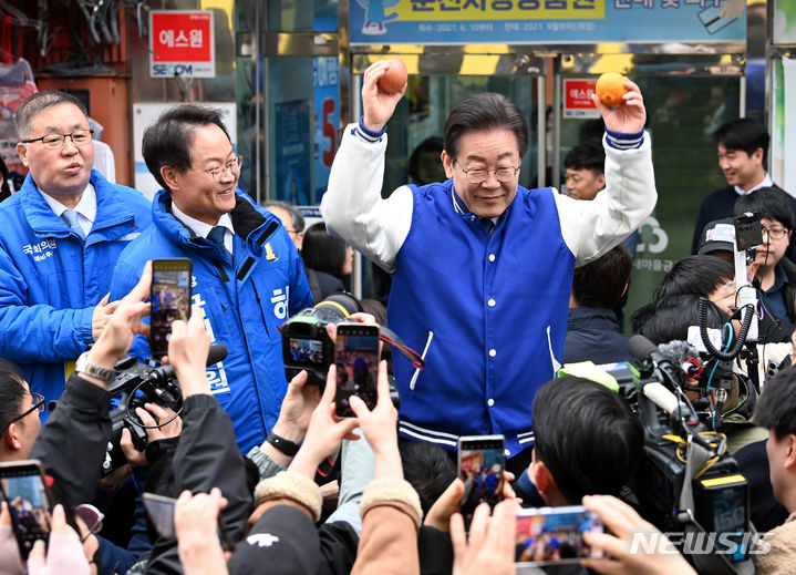 [춘천=뉴시스] 이영환 기자 = 이재명 더불어민주당 대표가 19일 오전 강원 춘천시 명동거리에서 시민들에게 선물 받은 한라봉과 사과를 손에 들고 인사를 나누고 있다. (공동취재) 2024.03.19. photo@newsis.com