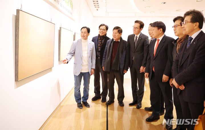 [창원=뉴시스] 조성제(맨왼쪽) 사진작가가 지난 25일 저녁 BNK경남은행갤러리에서 열린 '조성제 사진전' 오픈 행사에 참석한 내빈들에게 전시 작품에 대해 설명하고 있다.(사진=최종수 환경사진가 제공) 2024.03.26. photo@newsis.com