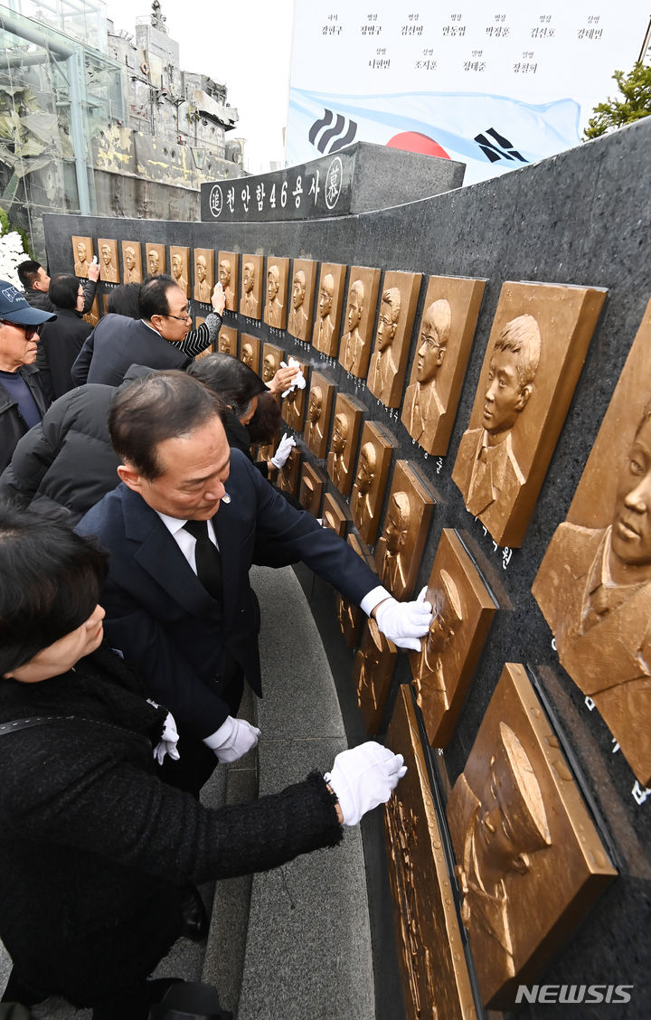 [평택=뉴시스] 김종택기자 = 제14주기 천안함 46용사 추모식이 거행된 26일 경기도 평택시 해군 제2함대사령부에서 유가족들이 추모비에 새겨진 얼굴을 어루만지고 있다. 이날 추모식에는 유가족, 천암함 피격사건 참전장병, 2함대 장병 및 군무원 등 200여 명이 참석했다. 2024.03.26. jtk@newsis.com