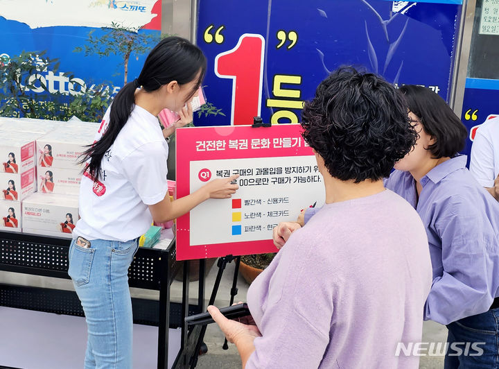 [세종=뉴시스]지난해 경상북도 포항 지역 복권판매점에서 진행된 ‘건전문화 캠페인’에서 한 시민이 복권 관련 퀴즈 이벤트에 참여하고 있다.(사진=동행복권 제공)