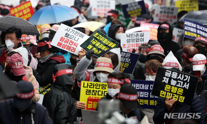 [서울=뉴시스] 김선웅 기자 = 홍콩ELS피해자들이 29일 서울 여의도의 한 은행 앞에서 집회를 열고 금융상품 손실 보상을 촉구하고 있다. 2024.03.29. mangusta@newsis.com