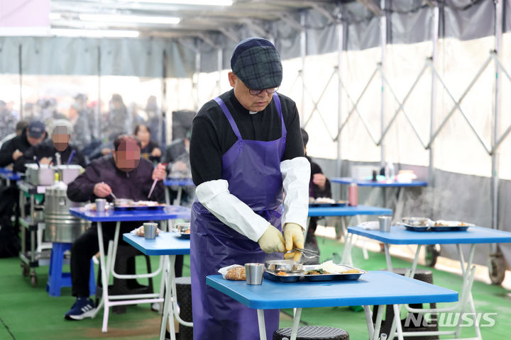 [서울=뉴시스] 박진희 기자 = 천주교 한마음한몸운동본부 무료급식소 '명동밥집' 센터장 백광진 신부가 29일 서울 중구 명동성당 내 명동밥집 무료급식소에서 배식을 하고 있다. 2024.03.30. pak7130@newsis.com