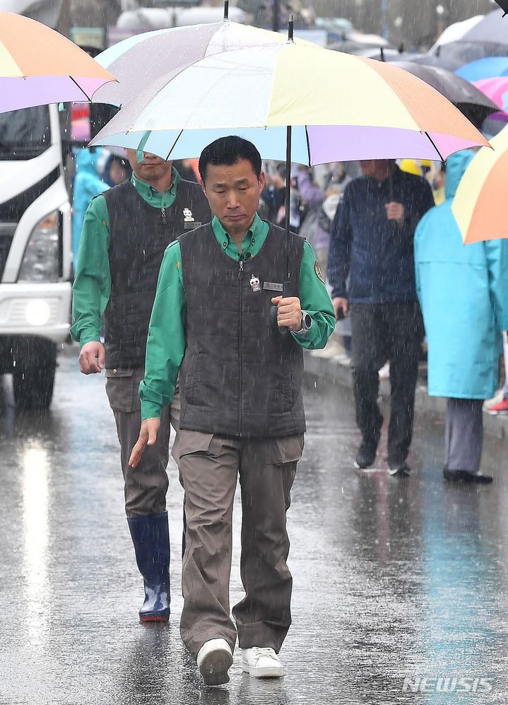 [용인=뉴시스] 사진공동취재단 = 강철원 사육사가 3일 오전 경기 용인 에버랜드 장미원에서 중국으로 떠나는 푸바오를 싣고 있는 무진동 특수 차량과 함께 걷고 있다. 2024.04.03. photo@newsis.com