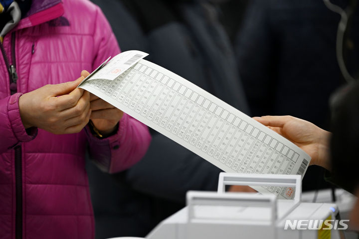 [광주=뉴시스] 이영주 기자 = 제22대 총선 사전투표 첫날인 5일 오전 광주 북구 오치1동행정복지센터에 마련된 사전투표소에서 한 유권자가 비례대표정당용 투표 용지를 받아들고 있다. 2024.04.05. leeyj2578@newsis.com