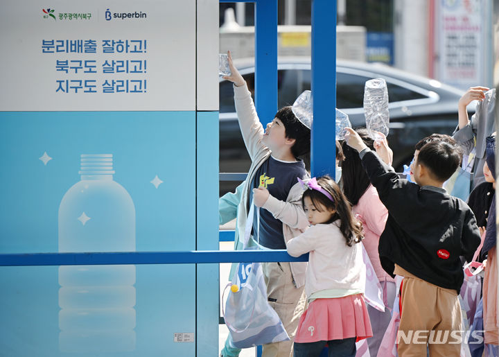 [광주=뉴시스] 박기웅 기자 = 9일 오전 광주 북구청직장어린이집 아이들이 어린이집에서 분리 수거한 투명 페트병을 전남대 스포츠센터 앞 무인회수기에 넣고 있다. 2024.04.09. pboxer@newsis.com