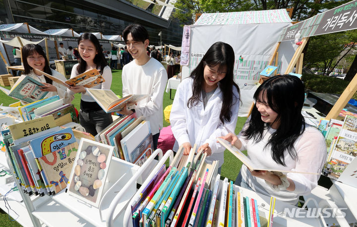 [서울=뉴시스] 조성우 기자 = 12일 오후 서울 서초구 국립중앙도서관 디지털도서관 앞에서 열린 도서관의 날에 미리 만나는 서초 책 있는 거리 행사장에서 학생들이 책을 보고 있다. 2024.04.12. xconfind@newsis.com