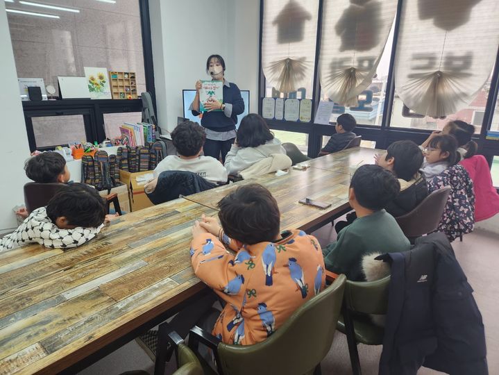 [당진=뉴시스] 지난 3월 12일 당진형 초등돌봄 사업에 선정된 기지초 인근 놀이문화판 놀이터 교실에서 아이들이 선생님의 책 설명을 듣고 있다. (사진=당진시 제공) 2024.04.17. *재판매 및 DB 금지