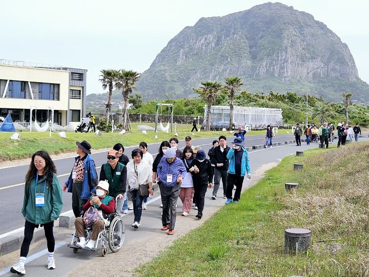 [제주=뉴시스] 제주도와 제주관광공사가 제주 무장애 여행 주간을 맞아 19일 오후 진행한 '제주 무장애 올레길 걷기' 행사 참가자들이 올레길 10코스를 걷고 있다. (사진=제주관광공사 제공) 2024.04.19. photo@newsis.com *재판매 및 DB 금지