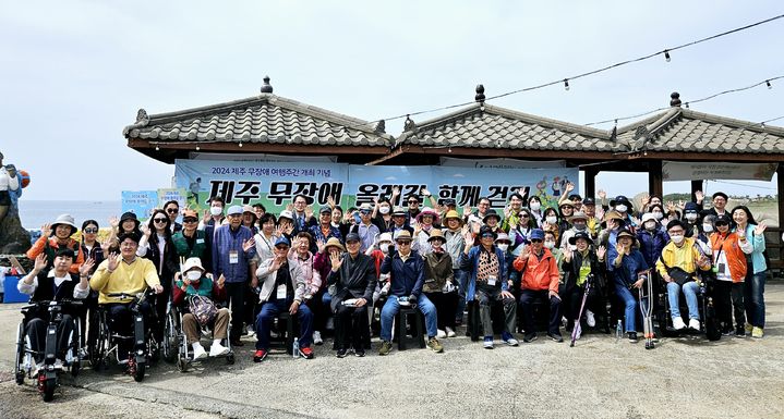[제주=뉴시스] 제주도와 제주관광공사가 제주 무장애 여행 주간을 맞아 19일 오후 진행한 '제주 무장애 올레길 걷기' 행사 참가자들이 기념 촬영을 하고 있다. (사진=제주관광공사 제공) 2024.04.19. photo@newsis.com *재판매 및 DB 금지