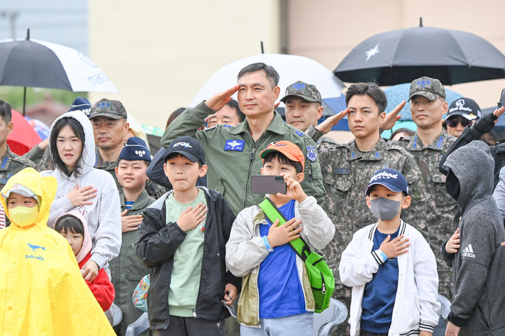 [대구=뉴시스] 공군 제11전투비행단 구상모 단장이 대구 공군기지에서 열린 '제45회 space challenge 2024 in 대구'에서 관람객들과 함께 국기에 대한 경례를 하고 있다. (사진=공군 제11전투비행단 제공) 2024.04.21. photo@newsis.com *재판매 및 DB 금지
