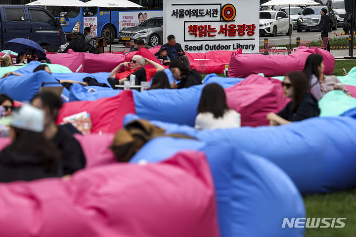 [서울=뉴시스] 정병혁 기자 = 21일 서울 중구 서울광장에 조성된 책읽는 서울광장을 찾은 시민들이 휴식을 취하고 있다. 2024.04.21. jhope@newsis.com