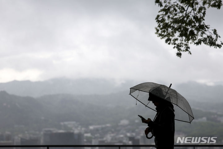 [서울=뉴시스] 정병혁 기자 = 비가 내린 24일 오전 서울 중구 남산에서 한 시민이 우산을 쓴 채 도심을 바라보고 있다. 2024.04.24. jhope@newsis.com