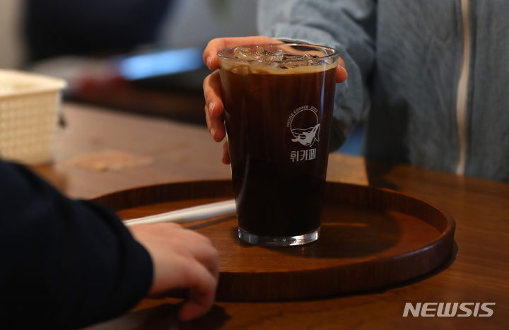 [서울=뉴시스] 김혜진 기자 = 김영우(28) 바리스타가 지난 22일 서울 동대문구 휘카페 1호점에서 뉴시스와 인터뷰에 앞서 손님에게 커피를 건네고 있다. 2024.04.28. jini@newsis.com