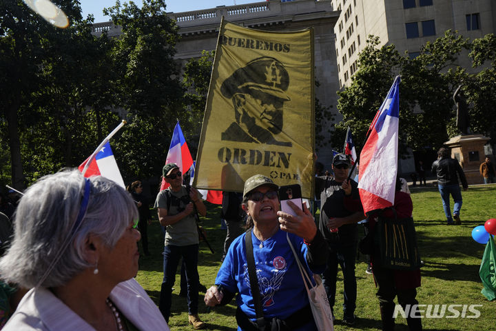 [산티아고( 칠레)= AP/뉴시스] 칠레의 수도 산티아고의 시위대가 군사쿠데타로 장기집권했던 아우구스토 피노체트장군의 초상화를 든채 시내에서 "우리는 질서를 원한다"며 27일(현지시간) 시위를 벌이고 있다. 칠레의 비오비오 지역에서는 27일 신고를 받고 출동한 경찰관 3명이 총격을 당해 죽고 차량이 불태워지는 테러사건이 발생했다. 2024. 04. 28. 