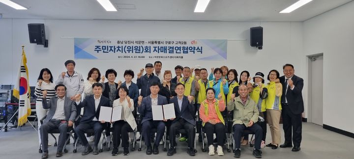 [당진=뉴시스] 지난 27일 당진 석문문화스포츠센터에서 석문면과 고척2동이 지역 교류 활성화 등을 위해 자매결연을 맺은 후 참석자들이 협약서를 들고 단체로 기념 사진을 찍고 있다. (사진=당진시 제공) 2024.04.29. photo@newsis.com *재판매 및 DB 금지