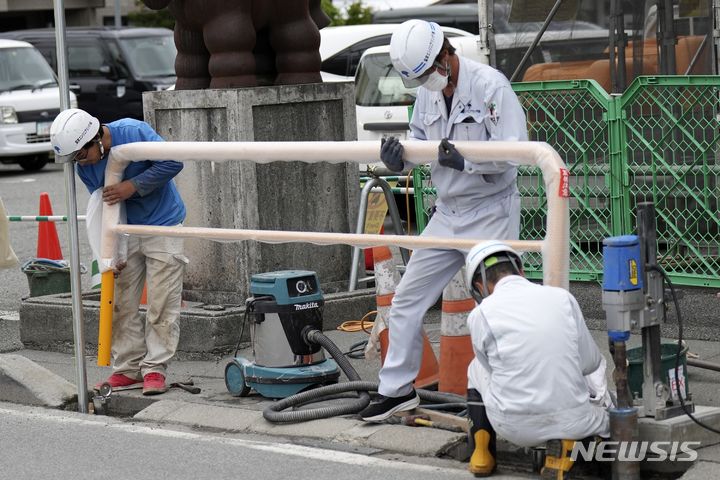 [야마나시현=AP/뉴시스] 4월 30일 일본 야마나시현 후지카와구치코에서 관계자들이 로손 편의점 인근에 바리게이트를 설치하고 있다. 이곳은 로손 편의점 뒤로 펼쳐진 후지산을 찍기 위한 관광객들의 비매너 행동에 몸살을 앓고 있다. 2024.05.29.