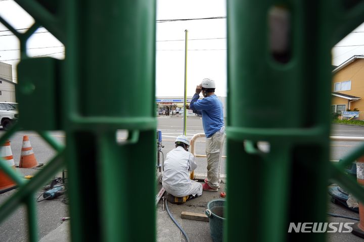 [야마나시현=AP/뉴시스] 4월 30일 일본 야마나시현 후지카와구치코에서 관계자들이 로손 편의점 인근에 바리게이트를 설치하고 있다. 이곳은 로손 편의점 뒤로 펼쳐진 후지산을 찍기 위한 관광객들의 비매너 행동에 몸살을 앓고 있다. 2024.05.29.