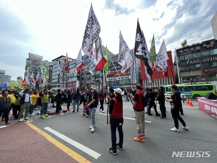 [천안=뉴시스] 박우경 기자=근로자의 날인 1일 오전 충남 천안시 동남구 신부동 천안신세계 앞 도로에서 민주노총 세종충남지역본부 주최로 '양회동열사 정신계승!, 윤석열정권퇴진!, 모든 노동자의 노동권 보장!'을 촉구하는 2024 세계노동절 세종충남대회가 열린 가운데 조합원들이 깃발을 들고 행진하고 있다 2024.5.1. spacedust1@newsis.com