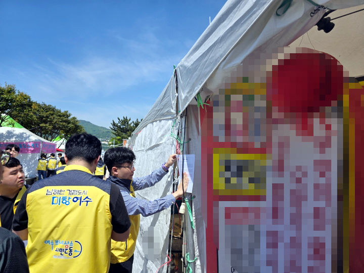 [여수=뉴시스] 여수시청 공무원들이 2일 여수거북선축제장 인근 해양공원 등에 무단 설치된 상가 천막 철거를 요구하는 계고장을 붙이고 있다. (사진=독자 제공) 2024.05.02. photo@newsis.com *재판매 및 DB 금지