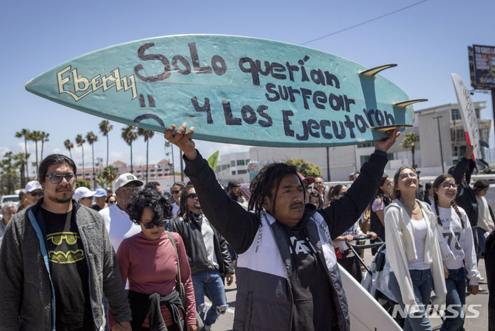 [엔시나다( 멕시코)= AP/뉴시스] 멕시코의 관광지 엔시나다 해변도시에서 서핑하던 외국인들이 실종, 살해된 데 대해 5월 4일 "서핑한 죄로 처형했나"라고 쓴 보드를 들고 항의하는 시위대. 멕시코에서는 호주와 미국 국적의 외국인 서핑객들을 살해하고 트럭을 빼앗은 사건이 일어나 경찰이 수사를 진행 중이다. 2024. 05. 06. 