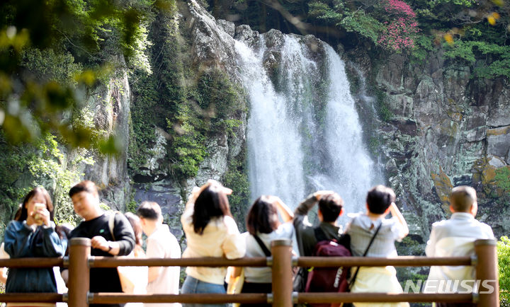 [서귀포=뉴시스] 우장호 기자 = 맑은 날씨를 회복한 6일 오전 제주 서귀포시 강정동 엉또폭포를 찾은 관광객들이 절벽 아래로 떨어지는 시원한 물줄기를 감상하고 있다. 평소 물이 흐르지 않는 엉또폭포는 전날 한라산에 900㎜가 넘는 폭우가 쏟아지자 좀처럼 보기 힘든 장관을 연출했다. 2024.05.06. woo1223@newsis.com