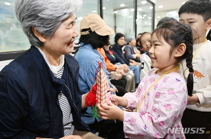 [수원=뉴시스] 김종택기자 = 어버이날을 하루 앞둔 7일 경기도 수원시 팔달노인복지관을 찾은 어린이들이 고사리손으로 할아버지 할머니께 카네이션을 달아주고 있다. 2024.05.07. jtk@newsis.com