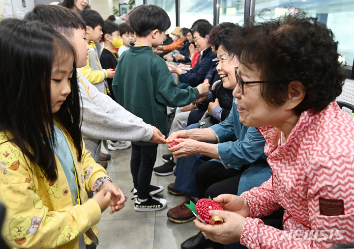 [수원=뉴시스] 김종택기자 = 어버이날을 하루 앞둔 7일 경기도 수원시 팔달노인복지관을 찾은 어린이들이 고사리손으로 할아버지 할머니께 카네이션을 달아주고 있다. 2024.05.07. jtk@newsis.com