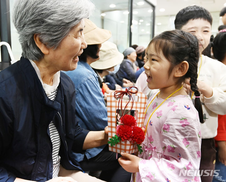 [수원=뉴시스] 김종택기자 = 사진은 지난해 5월 7일 어버이날(5월 8일)을 하루 앞두고 경기도 수원시 팔달노인복지관을 찾은 어린이들이 고사리손으로 할아버지 할머니께 카네이션을 달아주고 있는 모습. 2024.05.07. jtk@newsis.com