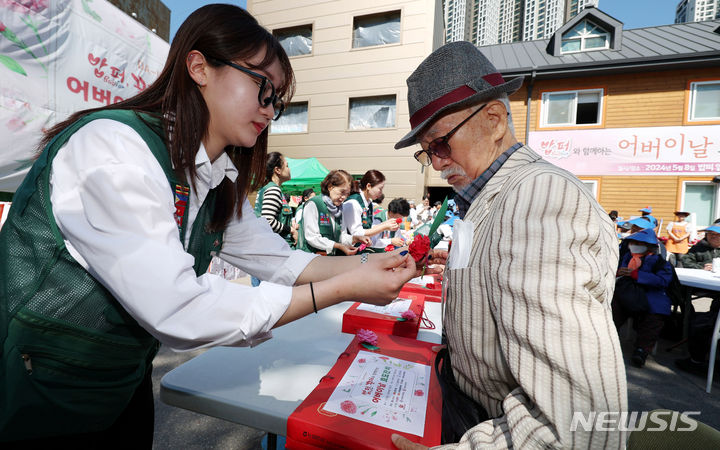 [서울=뉴시스] 추상철 기자 = 어버이날인 8일 오전 서울 동대문구 밥퍼나눔운동본부 앞마당에서 열린 다일공동체의 '어버이날 효도잔치'에서 자원봉사자가 어르신에게 카네이션을 달아 주고 있다. 2024.05.08. scchoo@newsis.com