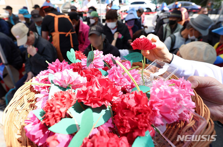 [서울=뉴시스] 추상철 기자 = 어버이날인 8일 오전 서울 동대문구 밥퍼나눔운동본부 앞마당에서 열린 다일공동체의 '어버이날 효도잔치'에서 자원봉사자들이 어르신에게 카네이션을 달아 주고 있다. 2024.05.08. scchoo@newsis.com