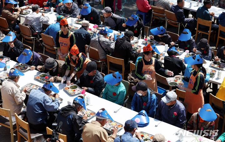 [서울=뉴시스] 추상철 기자 = 어버이날인 8일 오전 서울 동대문구 밥퍼나눔운동본부 앞마당에서 열린 다일공동체의 '어버이날 효도잔치'에서 자원봉사자들이 어르신에게 무료배식을 하고 있다. 2024.05.08. scchoo@newsis.com