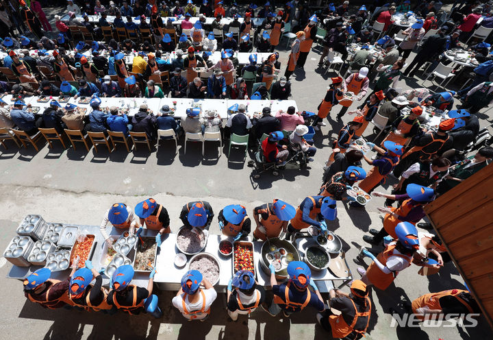 [서울=뉴시스] 추상철 기자 = 어버이날인 8일 오전 서울 동대문구 밥퍼나눔운동본부 앞마당에서 열린 다일공동체의 '어버이날 효도잔치'에서 자원봉사자들이 어르신에게 무료배식을 하고 있다. 2024.05.08. scchoo@newsis.com