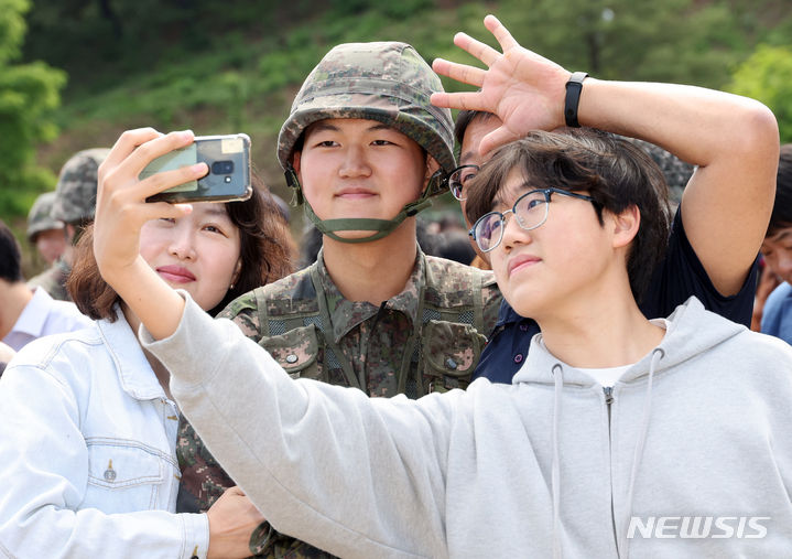 [세종=뉴시스] 강종민 기자 = 어버이날인 8일 세종시 육군 32사단 신병교육대대 연병장에서 열린 수료식에서 한 장병이 가족들과 기념촬영을 하고 있다. 2024.05.07. ppkjm@newsis.com