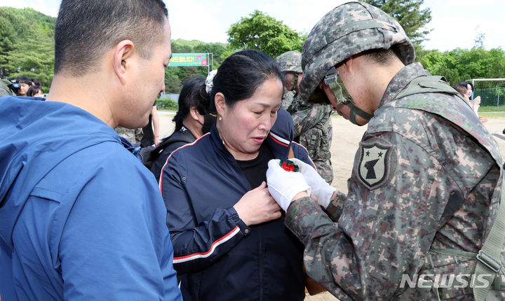 [세종=뉴시스] 강종민 기자 = 어버이날인 8일 세종시 육군 32사단 신병교육대대 연병장에서 열린 수료식에서 한 장병이 부모 가슴에 카네이션을 달아 주고 있다. 2024.05.07. ppkjm@newsis.com