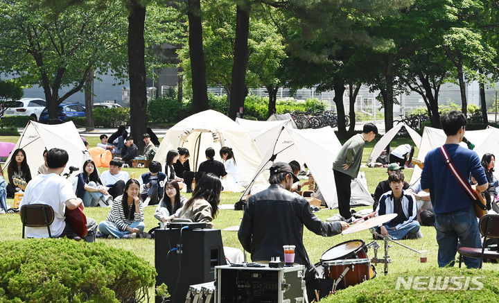 [수원=뉴시스] 김종택기자 = 화창한 날씨를 보인 9일 경기도 수원시 성균관대학교 자연과학캠퍼스 잔디밭에서 '북 피크닉' 행사에 참여한 학생들이 공연을 관람하고 있다. 2024.05.09. jtk@newsis.com