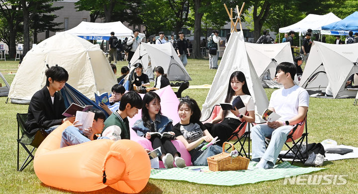 [수원=뉴시스] 김종택기자 = 9일 경기도 수원시 성균관대학교 자연과학캠퍼스 잔디밭에서 '북 피크닉' 행사에 참여한 학생들이 이야기를 나누며 책을 읽고 있다. 2024.05.09. jtk@newsis.com