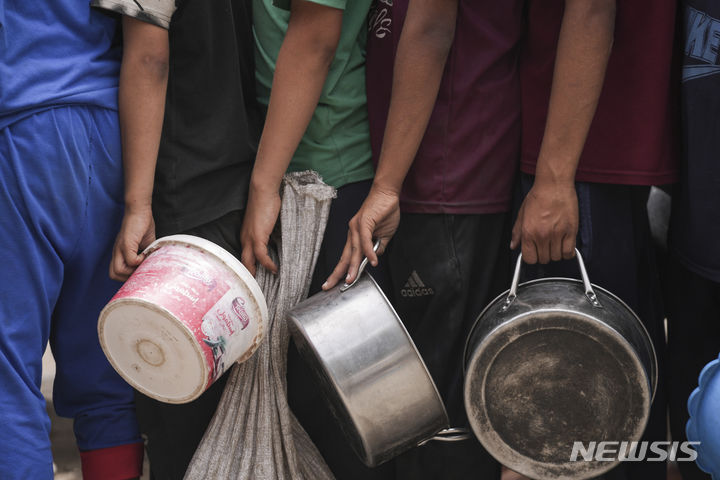 [가자지구=AP/뉴시스] 지난 10일(현지시각) 가자지구 데이르 알발라에서 식량을 배급받으려는 팔레스타인 난민들이 식기를 들고 순서를 기다리고 있다. 2024.05.12.