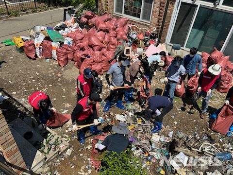 [파주=뉴시스] 경기 파주시 월롱면 한 주택에 쌓여 있는 쓰레기들을 봉사단체 등이 참여해 수거하고 있다.(사진=파주시 제공) 