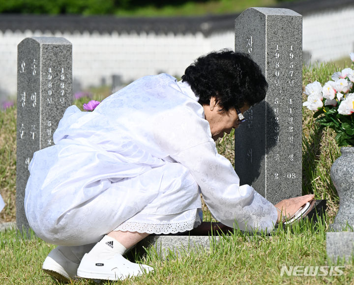 [광주=뉴시스] 박기웅 기자 = 5·18민주화운동 44주기를 하루 앞둔 17일 오전 광주 북구 운정동 국립5·18민주묘지에서 고(故) 장재철 열사의 어머니 김점례 여사가 아들의 사진을 쓰다듬고 있다. 2024.05.17. pboxer@newsis.com