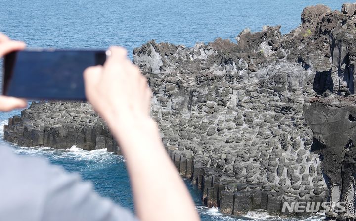 [제주=뉴시스] 오영재 기자 = 맑고 선선한 날씨를 보인 18일 오전 제주 서귀포시 중문대포 주상절리대 전망대에서 탐방객이 단체 사진을 찍고 있다. 천연기념물 제443호인 대포 주상절리대는 두꺼운 용암이 빠르게 식는 과정에서 형성된 육각형 모양의 현무암 지대다. 2024.05.18. oyj4343@newsis.com