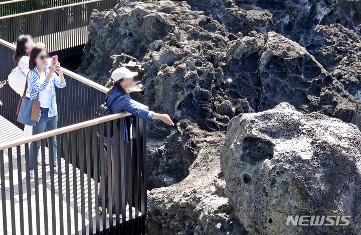 [뉴시스=제주] 오영재 기자 = 맑고 선선한 날씨를 보인 18일 오전 제주 서귀포시 중문대포 주상절리대 전망대에서 외국인 관광객이 바위에 동전을 던지고 있다. 2024.05.18. oyj4343@newsis.com
