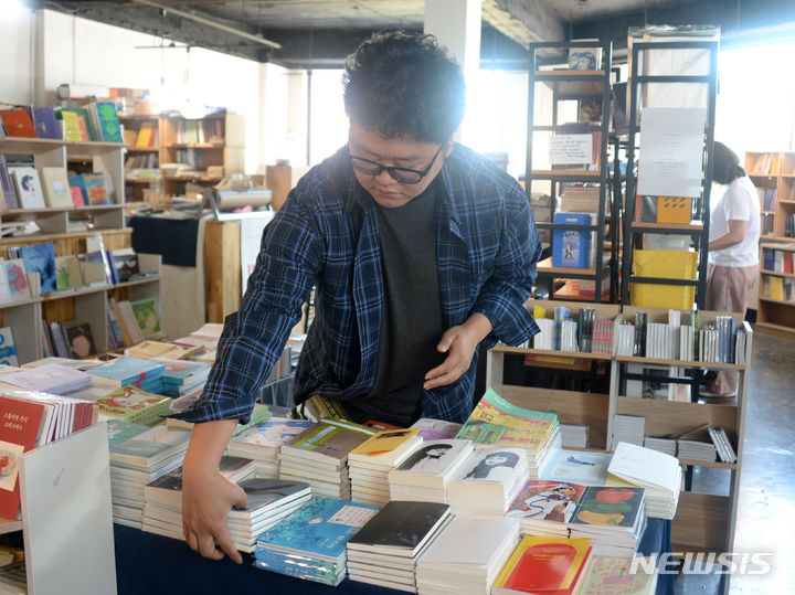 [전주=뉴시스] 김얼 기자 = 이명규 에이커북스토어 사장이 18일 전북 전주시 완산구 중앙동에 위치한 에이커북스토어에서 손님을 맞이할 준비를 하며 책을 정리하고 있다. 2024.05.18. pmkeul@newsis.com