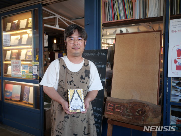 [전주=뉴시스] 강경호 기자 = 문수범 책방 토닥토닥 사장이 19일 전북 전주시 완산구 중동에 위치한 책방 토닥토닥 입구에서 서적을 들고 책방을 소개하고 있다. 2024.05.19. lukekang@newsis.com