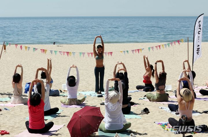 [부산=뉴시스] 하경민 기자 = 부산시가 운영하는 '해양치유 프로그램'의 하나인 해변요가가 열린 19일 부산 해운대구 해운대해수욕장 백사장에서 시민들이 강사들의 도움을 받아 요가를 배우고 있다. 해양치유 프로그램은 상반기 7월7일까지, 하반기 9월2일~10월29일 해운대·광안리·다대포·송정·송도·임랑·일광 해수욕장과 수영강, 영도 아미르공원 등지서 해변 어싱(맨발) 노르딕워킹과 선셋필라테스, 싱잉볼명상, 해변요가, 훌라댄스, 공-사운드배스, 펀더멘탈 등 프로그램을 진행한다. 2024.05.19. yulnetphoto@newsis.com