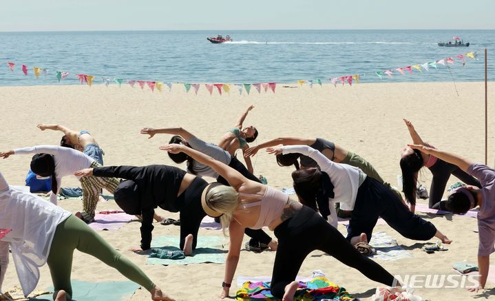 [부산=뉴시스] 하경민 기자 = 부산시가 운영하는 '해양치유 프로그램'의 하나인 해변요가가 열린 19일 부산 해운대구 해운대해수욕장 백사장에서 시민들이 강사들의 도움을 받아 요가를 배우고 있다.  해양치유 프로그램은 상반기 7월7일까지, 하반기 9월2일~10월29일 해운대·광안리·다대포·송정·송도·임랑·일광 해수욕장과 수영강, 영도 아미르공원 등지서 해변 어싱(맨발) 노르딕워킹과 선셋필라테스, 싱잉볼명상, 해변요가, 훌라댄스, 공-사운드배스, 펀더멘탈 등 프로그램을 진행한다. 2024.05.19. yulnetphoto@newsis.com